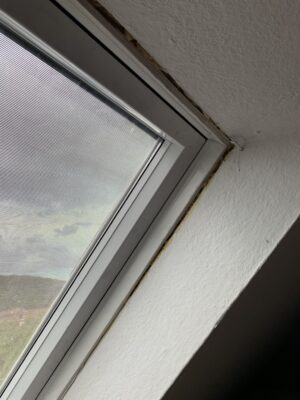 Detailaufnahme eines Dachfensters im unsanierten Zustand mit sichtbarer Lücke zwischen Fensterrahmen und Innenverkleidung.