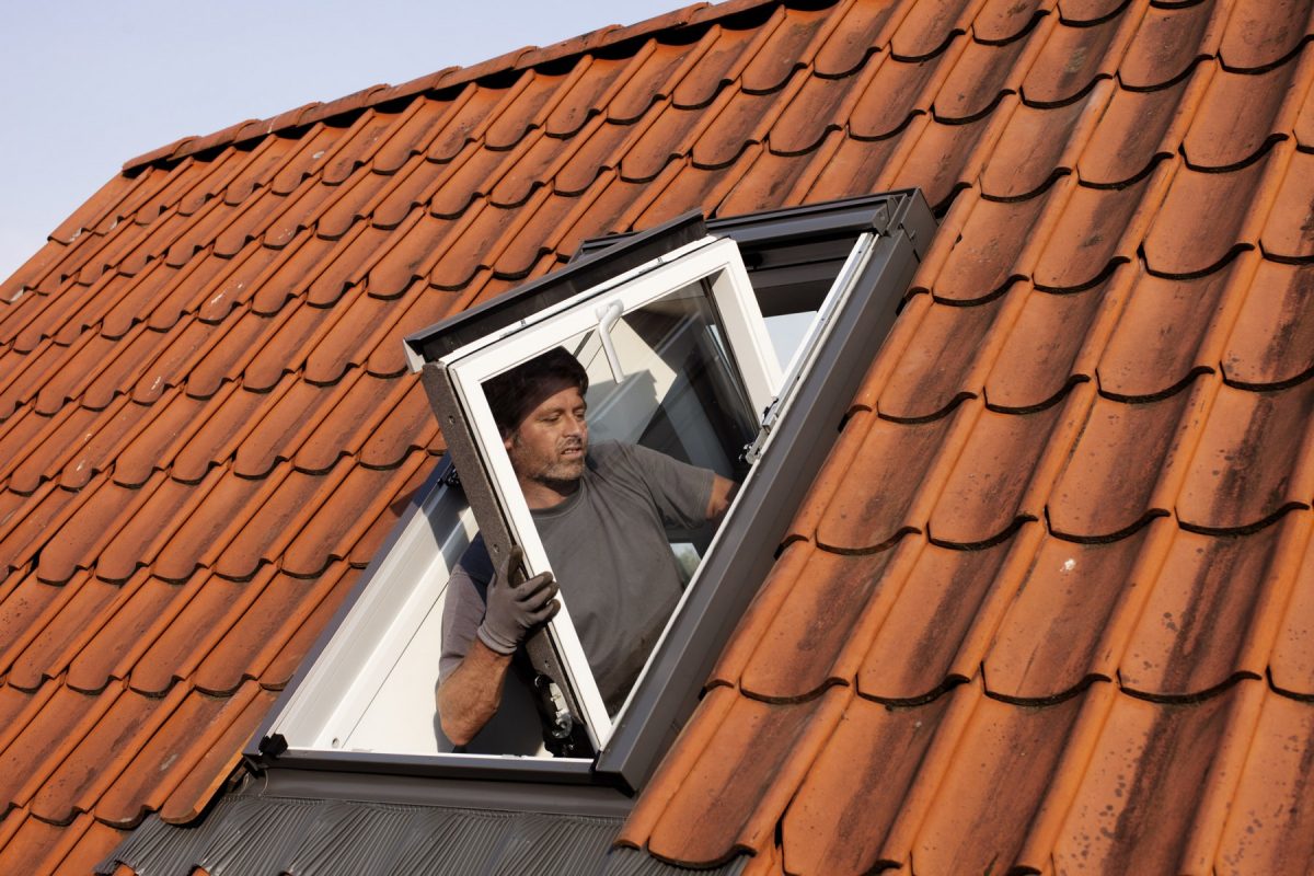 Der Flügelrahmen eines neuen Dachfensters wird beim Austausch in Würzburg durch einen Fachmann in den vorhandenen Blendrahmen eingesetzt.