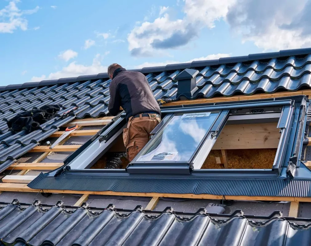 Ein Handwerker beim Dachfenster-Einbau in Würzburg.