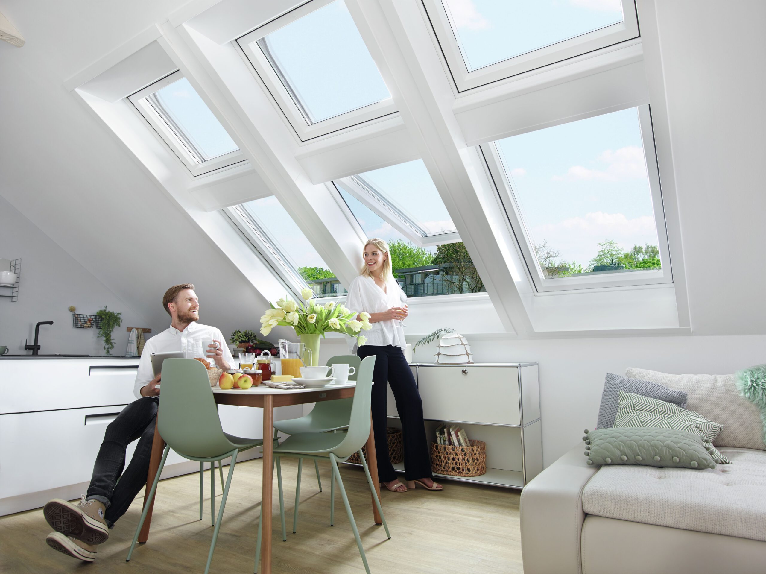 Ein Paar genießt sein Frühstück in einem hellen Raum mit 6 Dachfenstern und freut sich über den tollen Dachfenster-Service in Würzburg.
