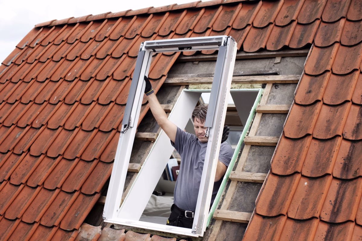 In Würzburg ist ein Handwerker dabei, ein Dachfenster zu tauschen.
