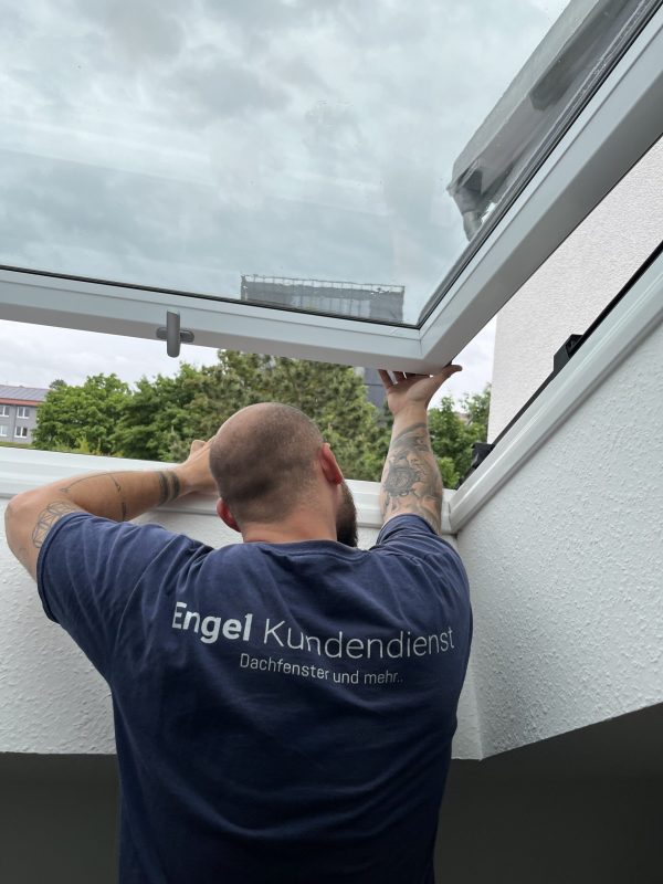 Lars Engel führt an einem Dachfenster die Wartung in Würzburg durch.