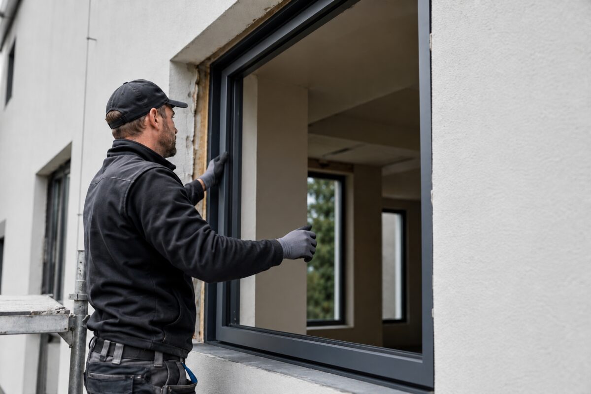 Ein Fensterexperte setzt beim Fenstertausch in Würzburg ein neues Fassadenfenster ein.