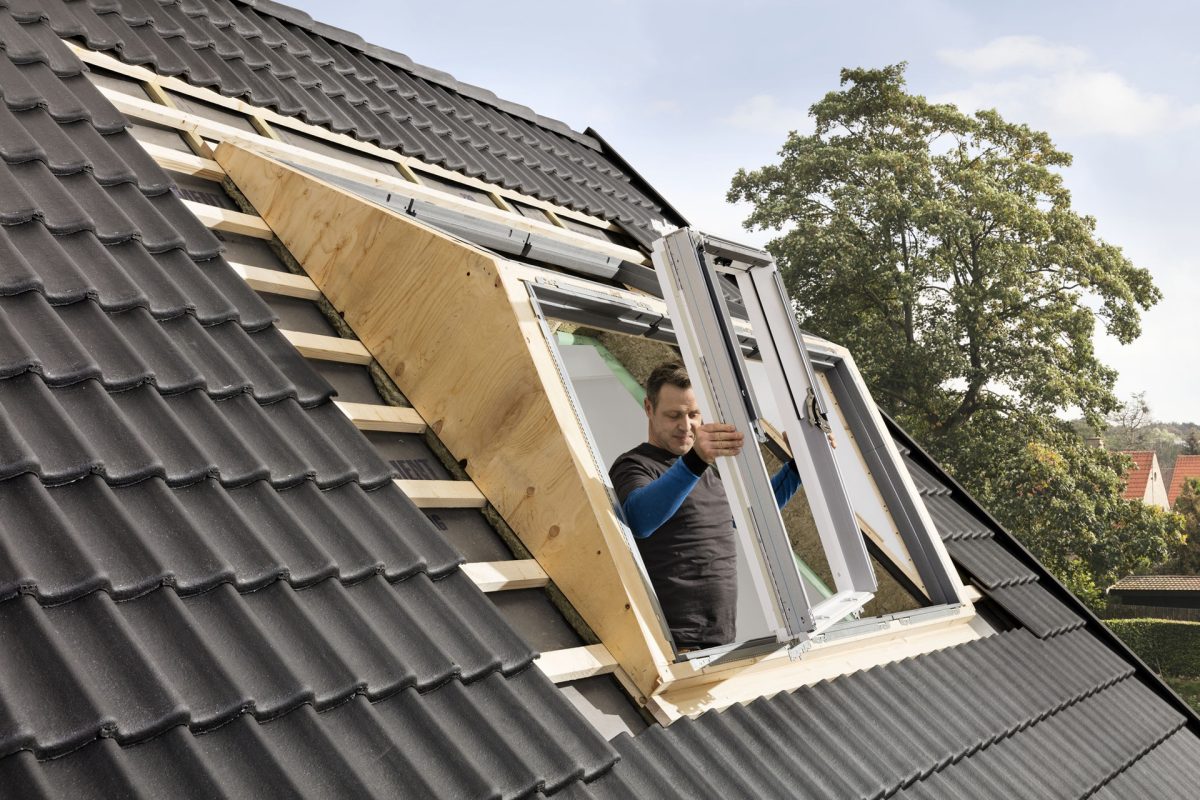 Ein Panorama-Dachfenster wird beim Einbauen durch einen Handwerker in Würzburg in den Rahmen eingesetzt.